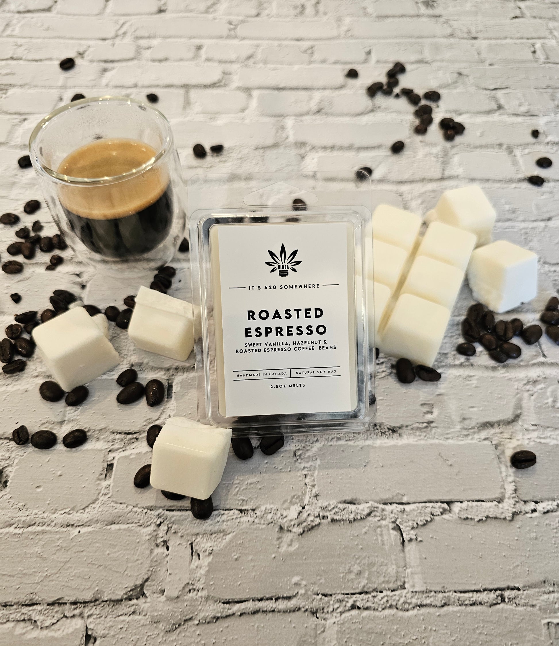 shot of roasted espresso in a clear cup next to cubes of soy wax with spilled coffee beans 