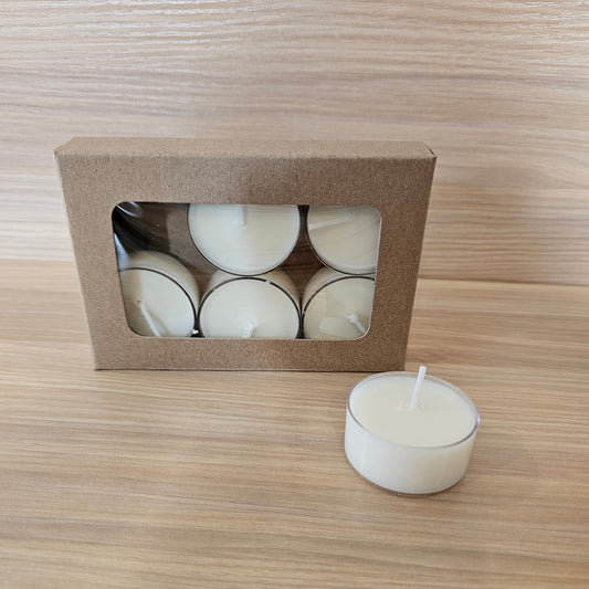 White tea light candles with a cardboard box on a wooden surface