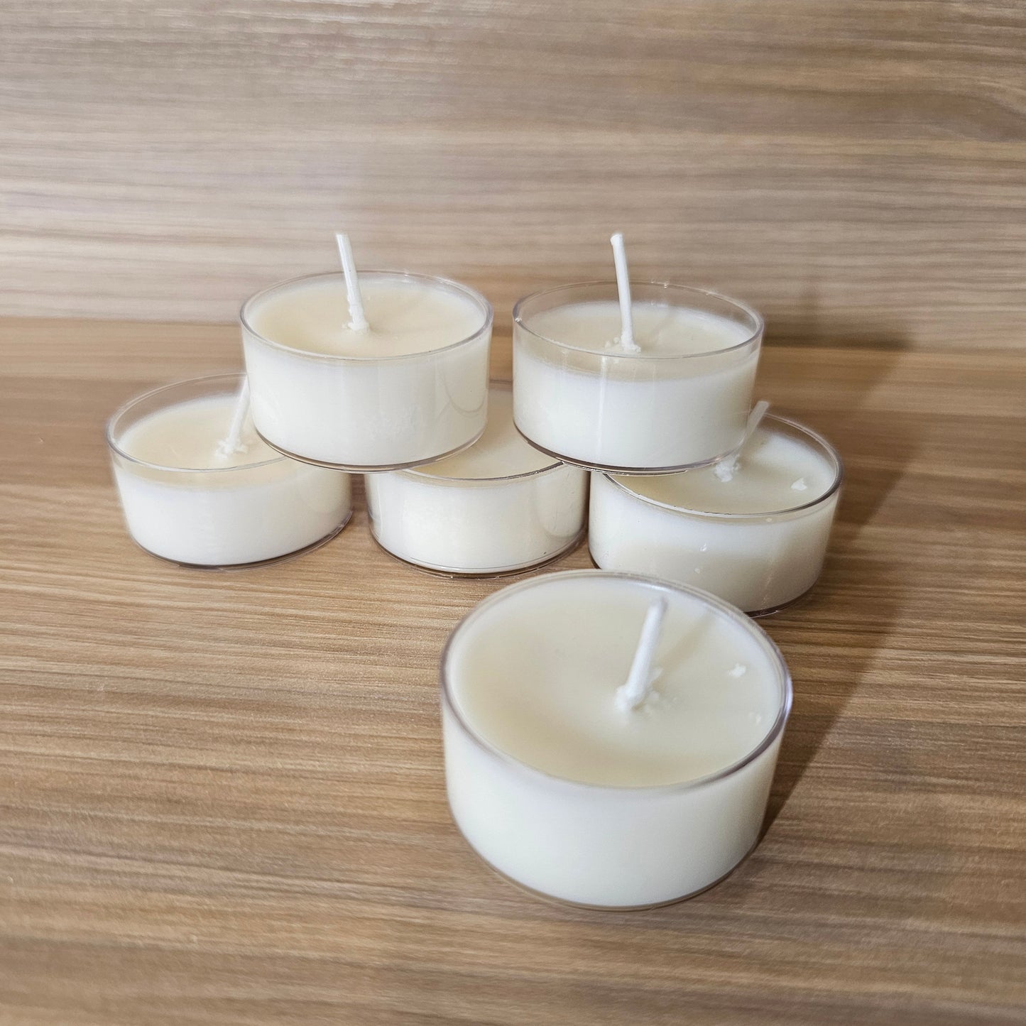 Set of white tealight candles on a wooden surface